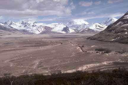 Photograph of ash flow in fore and middleground and snow-covered mountains in background