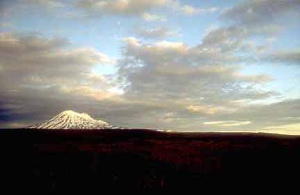Photograph of snow-covered volcano with dramatic sunset and clouds