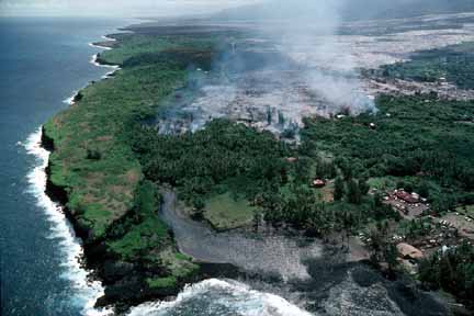 photo 064.  Low-elevation oblique aerial photo of lava flow nearing lagoon and ocean; houses burning as lava progresses to the sea