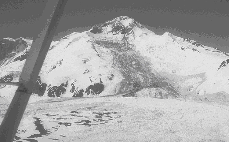 Figure 4. East flank of Iliamna Volcano. A mixed snow, rock, and ice avalanche deposit from the June 30, 1994 event is visible as the dark swath descending the east flank and turning to the left (south) out of the picture.